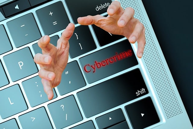 Computer with hands coming out from the keyboard around the word "cibercrime."